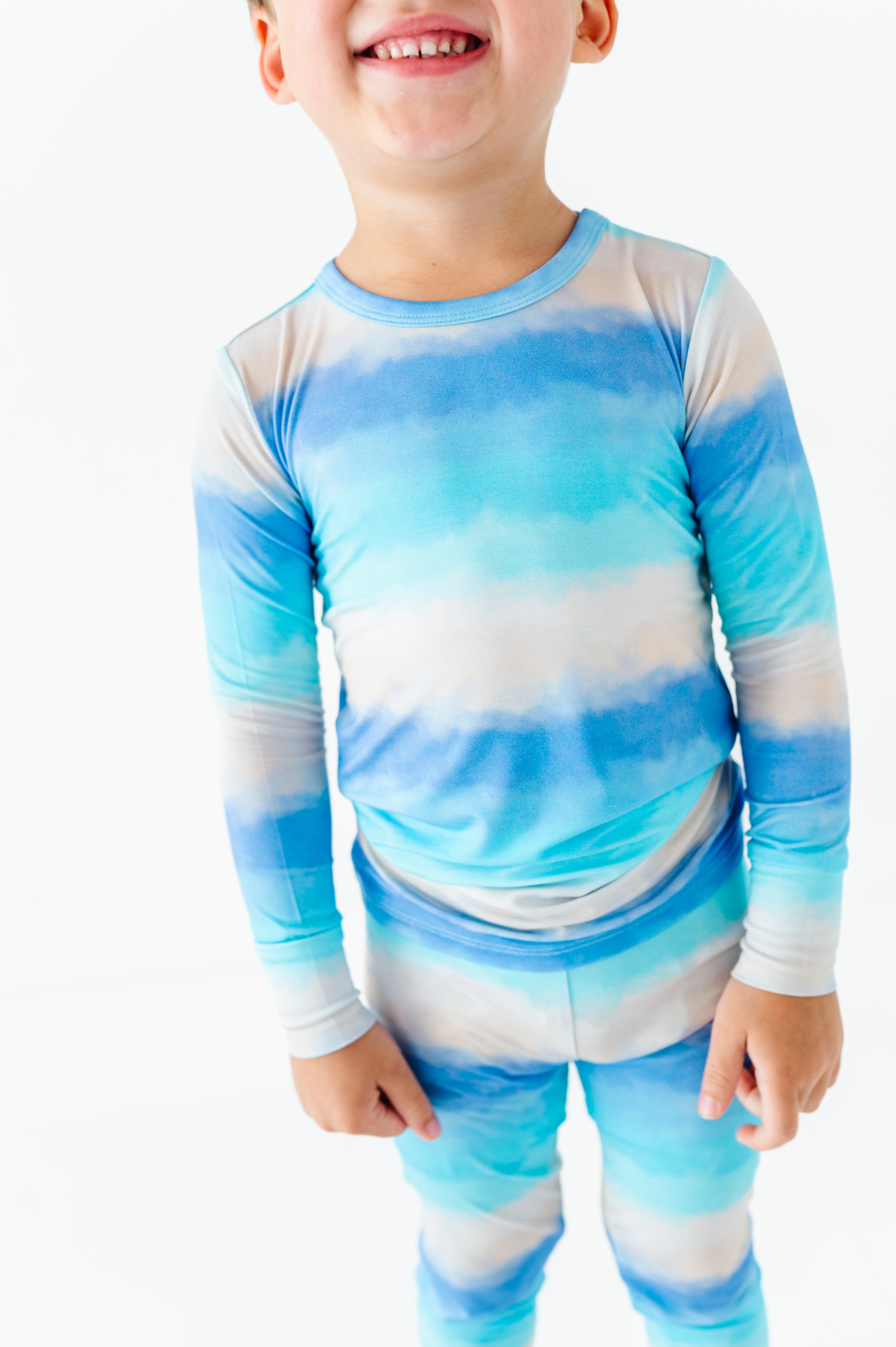 Child wearing a bamboo blue and white tie-dye long-sleeve shirt and pants on a white background
